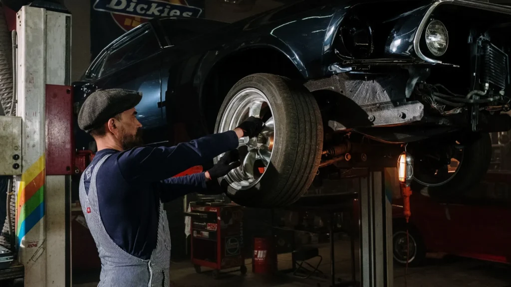 Automotive technician fitting CNC machined alloy wheel during car maintenance—highlighting CNC machining in vehicle parts manufacturing and repair