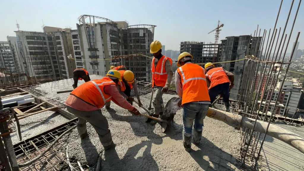 Construction workers pouring concrete on building site—CNC machining used in precision construction equipment and structural components