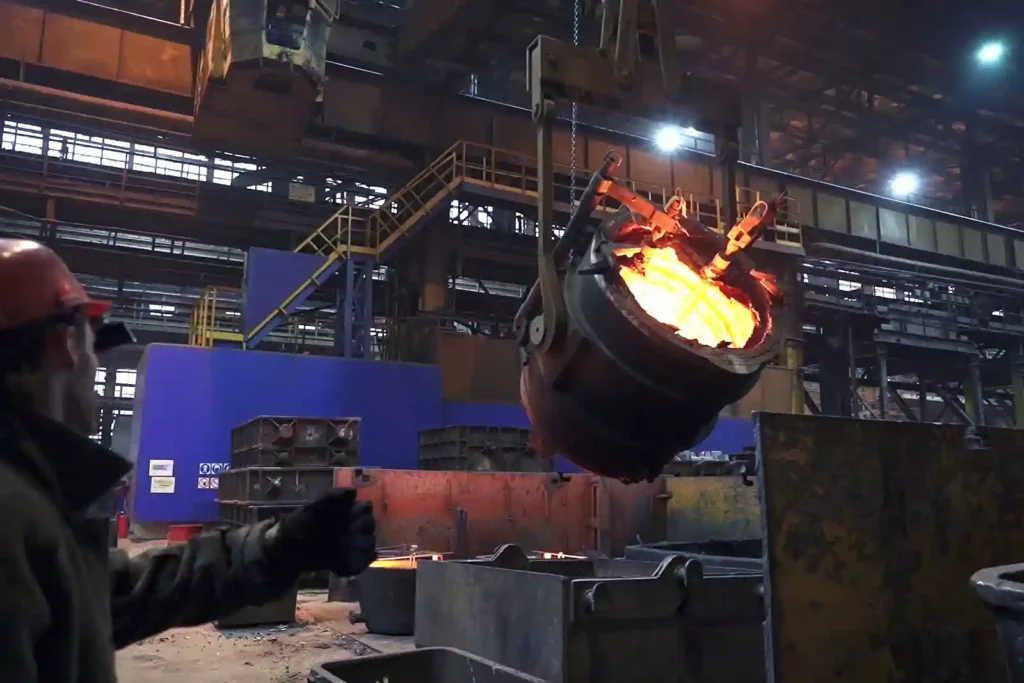 Molten metal pouring casting process in industrial foundry with worker handling furnace ladle